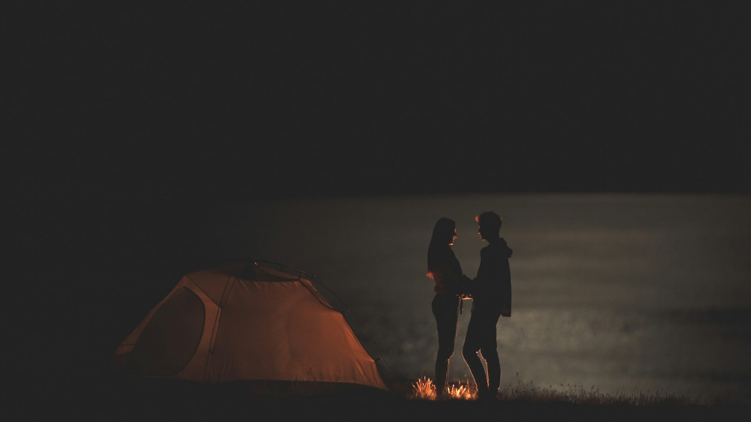 A couple enjoying the peaceful sunset scenery while camping outdoors