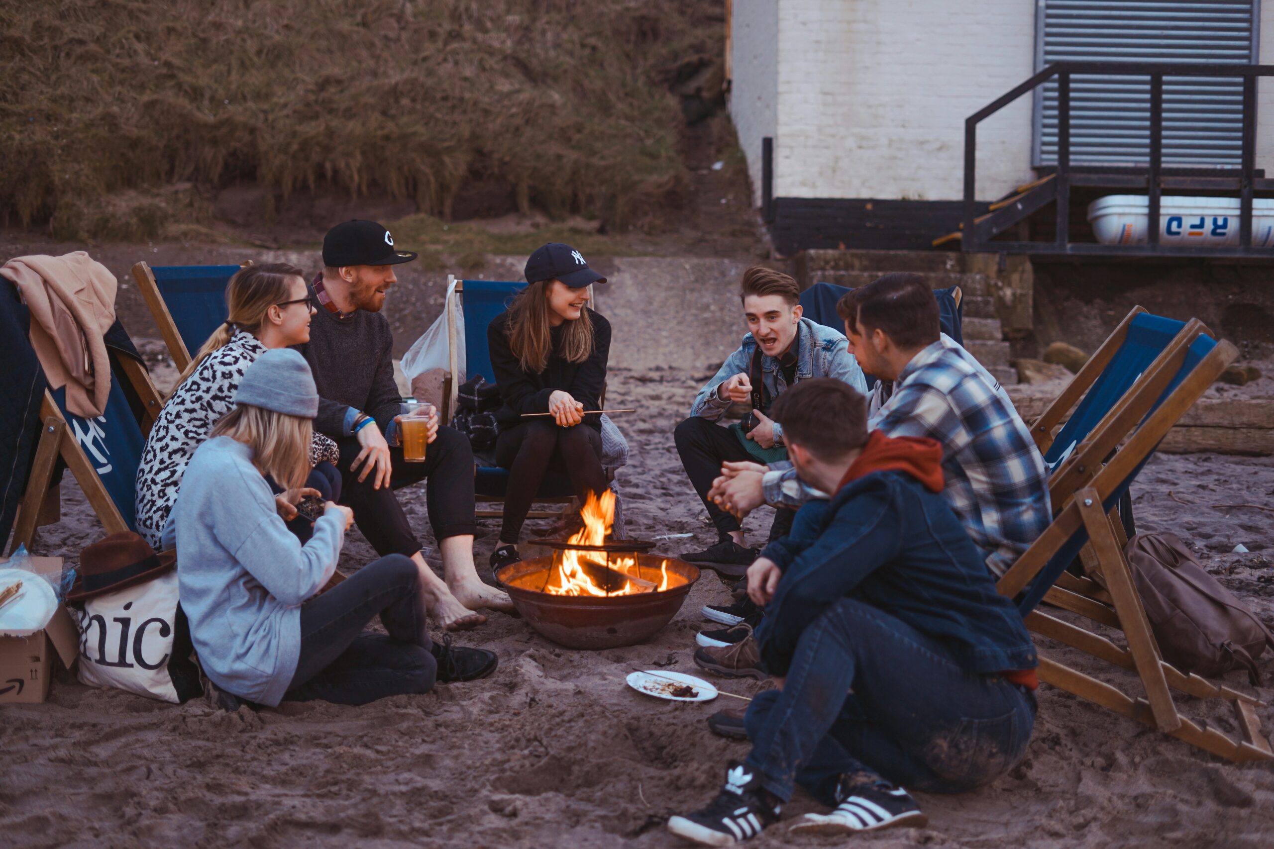 Adult Camping: Friends chatting with drinks by the campfire
